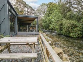 An outdoor seating area with a table by a river at Irt Cottage Seascale