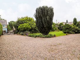 A garden with gravel driveway and trees at Prudhoe Cottage in Prudhoe