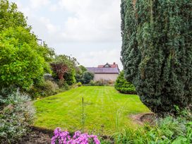 A garden with grass, flowers, and trees at Prudhoe Cottage in Prudhoe