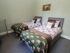A bedroom with two beds and a clothes rack at Prudhoe Cottage in Prudhoe