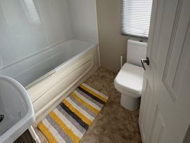 A bathroom with a bathtub, toilet, and sink at Lyons Robin Hood, Rhyl