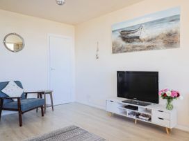 A living room with a television and an armchair at 16 Old Shipyard Centre in West Bay