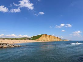 A beach with cliffs and a boat in the sea at 16 Old Shipyard Centre West Bay