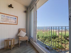 A balcony with a chair and side table at 16 Old Shipyard Centre in West Bay