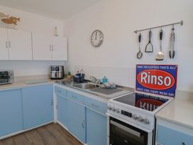 A kitchen with cabinets, sink, clock, and stove at 16 Old Shipyard Centre, West Bay