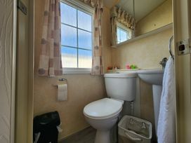 A bathroom with a toilet, sink, and mirror at Whitley bay parkdean resorts - 52 Beechfield, Whitley Bay