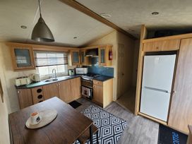 A kitchen with cabinets, appliances, and a dining table at Whitley bay parkdean resorts - 52 Beechfield, Whitley Bay