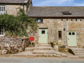 An outdoor view of a stone building with green doors and a red mailbox at Dashel Cottage at Dockwell Farm near Widecombe-In-The-Moor