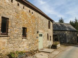 A stone building with windows and a green door at Dashel Cottage at Dockwell Farm near Widecombe-In-The-Moor