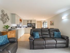 A living room with a kitchen area featuring a sofa and kitchen appliances at The Old Dairy near Liskeard