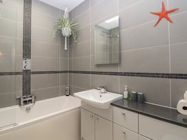 A bathroom with bathtub, sink, and mirror at The Old Dairy near Liskeard