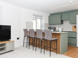 A kitchen with bar stools and cabinets at Greenswood Mews in Brixham