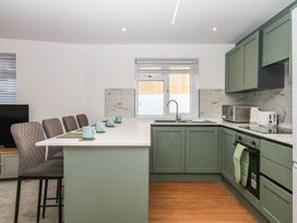 A kitchen with a sink, stove, and bar stools at Greenswood Mews in Brixham