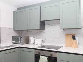 A kitchen with cabinets, microwave, kettle, and a knife block at Greenswood Mews in Brixham