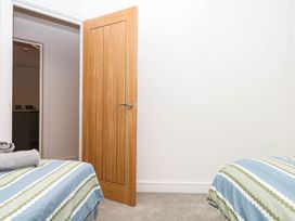 A bedroom with beds and an open door at Greenswood Mews in Brixham