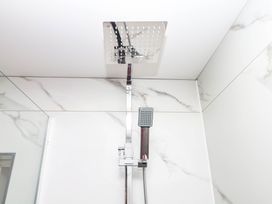 A shower head and handle in a modern bathroom at Greenswood Mews in Brixham
