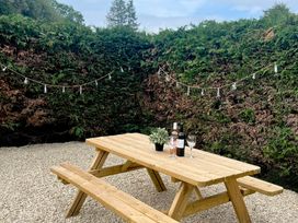 A garden with a wooden table and benches at Saddleback Bungalow in Llandrindod Wells