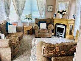 A living room with sofas, an armchair, and a fireplace at Sea Breeze A Beautiful 3 Bed Pet Friendly Retreat in Mablethorpe