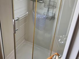 A shower with a glass door and shelves in the bathroom at Sea Breeze A Beautiful 3 Bed Pet Friendly Retreat Mablethorpe