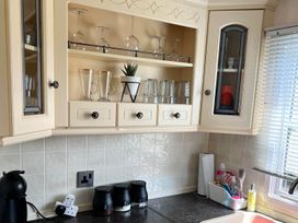 A kitchen with glassware and storage cabinets at Sea Breeze A Beautiful 3 Bed Pet Friendly Retreat, Mablethorpe