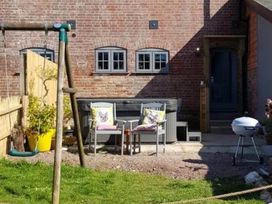 A garden with a swing, chairs, hot tub, and grill at 3 Bedroom Cottage Hot Tub Garden Parking Dunkeswell