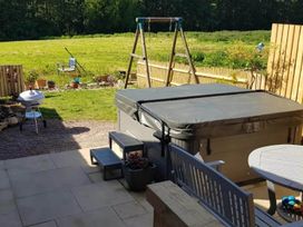 A garden with a hot tub, seating area, and swing set at 3 Bedroom Cottage Hot Tub Garden Parking Dunkeswell