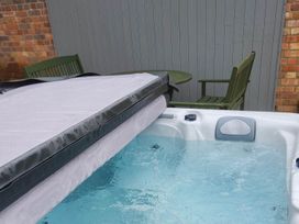 A hot tub with cover near a table and chair at 3 Bedroom Cottage Hot Tub Garden Parking Dunkeswell