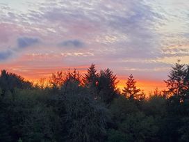 A sunset over trees with clouds in the sky at 3 Bedroom Cottage Hot Tub Garden Parking Dunkeswell