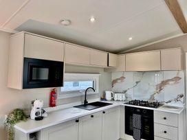 A kitchen with a sink, gas stove, microwave, and kettle at Lovely Holiday Home On Waxham Sands, Great Yarmouth