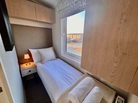 A bedroom with a single bed and bedside lamp at Lovely Holiday Home On Waxham Sands, Great Yarmouth