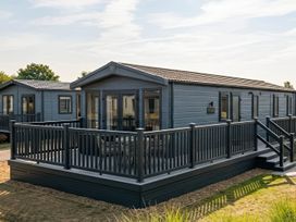 A mobile home with a deck and steps at Lovely Holiday Home On Waxham Sands near Waxham Sands Holiday Park