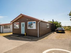 A wooden house with parked car and grass area at a property location