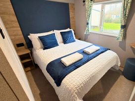 A bedroom with a double bed and window at Vintage 121 Southview Holiday Park Skegness