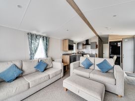 A living room with sofas and kitchen area at Primrose Valley 3Bed Caravan Sleeps 8 Pets Ok, Primrose Valley