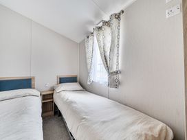 A bedroom with two single beds and patterned curtains at Primrose Valley 3Bed Caravan Sleeps 8 Pets Ok, Primrose Valley