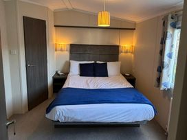 A bedroom with a bed and nightstand at 2Bed Ringwood Cabin incl Park Pass SelfCheckin Saint Leonards near Ferndown