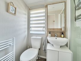 A bathroom with a toilet, sink, and mirror at Cayton Bay Holiday Park Kestrel40, Cayton Bay