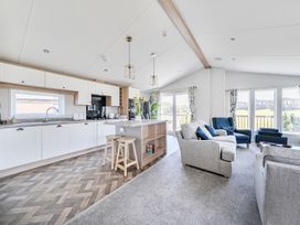 A kitchen with bar stools and living area at Atlantic Breeze Luxury Lodge sleep 6 Mullacott near Ilfracombe
