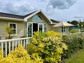 An outdoor view of a house with plants and an umbrella at Stunning Sleeps 6 Luxury Lodge Pets Mercia Marina near Willington, Derbyshire