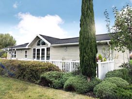 A house with a fence and bushes at Stunning Sleeps 6 Luxury Lodge Pets Mercia Marina near Willington, Derbyshire