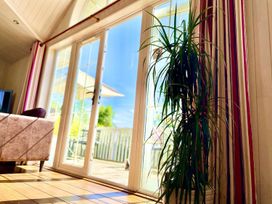 A living room with sliding glass doors and a plant at Stunning Sleeps 6 Luxury Lodge Pets Mercia Marina near Willington, Derbyshire