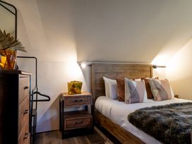 A bedroom with a bed, bedside table, lamp, and dresser