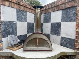 A pizza oven with a flue and utensils on a stone base outdoor