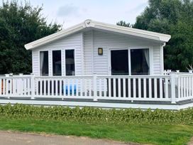 A cabin with a deck and windows at Meadows 33 Hot tub Southview Holiday Park in Skegness