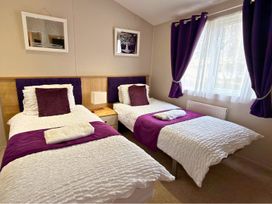 A bedroom with two beds and a nightstand at Meadows 33 Hot tub Southview Holiday Park Skegness