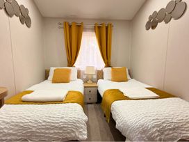 A bedroom with two single beds and a bedside table at Meadows 33 Hot tub Southview Holiday Park in Skegness