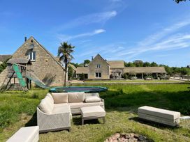 A garden with outdoor seating and a trampoline at Stunning 6 Bedroom Riverside Barn Cotswold Mill Ewan near Kemble