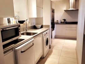 A kitchen with a microwave, sink, washing machine, and kettle at Stunning 6 Bedroom Riverside Barn Cotswold Mill in Ewan near Kemble