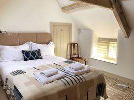 A bedroom with a double bed and wooden chair at Stunning 6 Bedroom Riverside Barn Cotswold Mill near Kemble