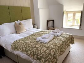 A bedroom with a bed and a chair at Stunning 6 Bedroom Riverside Barn Cotswold Mill in Ewan near Kemble